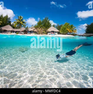 Uomo a nuotare in una laguna tropicale di fronte all'isola esotica Foto Stock