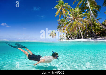 Uomo a nuotare in un chiaro acque tropicali di fronte all'isola esotica Foto Stock