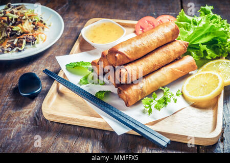 Fritti Croccanti involtini primavera con salsa di prugne e insalata, le fette di limone su un tavolo di legno Foto Stock