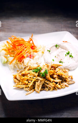 Shawarma di pollo o di Döner Kebab servendo con hummus e vegetale in piastra bianca sul tavolo di legno. Foto Stock