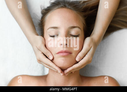 Giovane donna bionda che ricevere un massaggio della testa in un centro termale con gli occhi chiusi. Paziente di sesso femminile è di ricevere il trattamento dal terapista professionale. Foto Stock