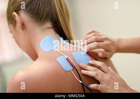 Elettrostimolazione in terapia fisica ad una giovane donna. Visita medica di controllo in corrispondenza della spalla in un centro di fisioterapia. Foto Stock