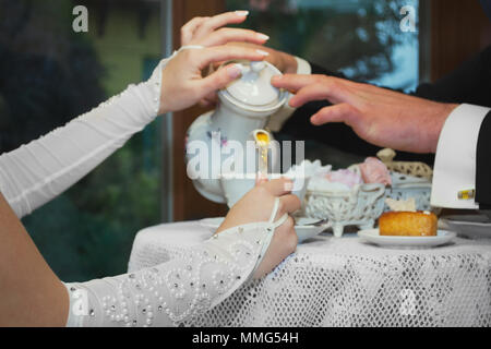 La sposa e lo sposo bere il tè presso la caffetteria. Versare insieme dal bollitore nella coppa Foto Stock
