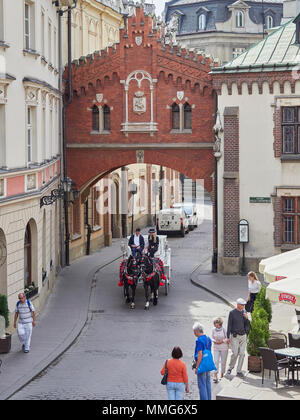 La Krakow Tourist carro trainato da cavalli passando sotto l'arco collegato alla chiesa in Pijarska St Polonia Foto Stock