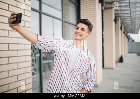 Giovane uomo bello tenendo selfie all'aperto in strada Foto Stock