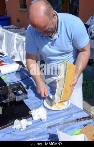 Mugena, Svizzera - 7 Maggio 2018: uomo preparare una porzione di raclette in Mugena sulle alpi svizzere Foto Stock