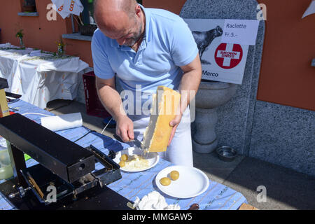 Mugena, Svizzera - 7 Maggio 2018: uomo preparare una porzione di raclette in Mugena sulle alpi svizzere Foto Stock