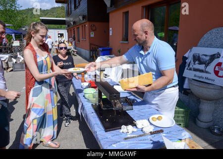 Mugena, Svizzera - 7 Maggio 2018: uomo preparare una porzione di raclette in Mugena sulle alpi svizzere Foto Stock