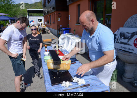 Mugena, Svizzera - 7 Maggio 2018: uomo preparare una porzione di raclette in Mugena sulle alpi svizzere Foto Stock