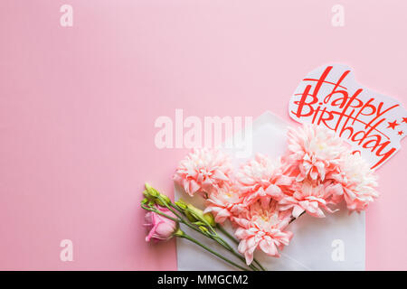 Busta bianca con una molla floreale. Piatto, laici top view.Buon Compleanno card con crisantemi Foto Stock