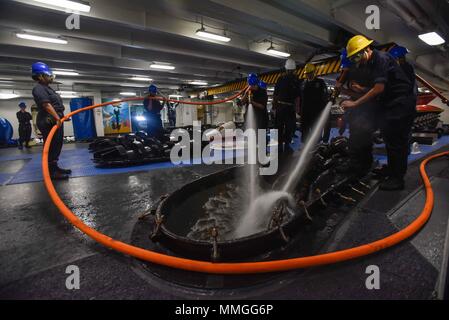 171006-N-CL027-047 PORTO DI HONG KONG (ott. 6, 2017) - sezione di coperta marinai lavare la catena di ancoraggio nel castello di prua della Marina è distribuita portaerei USS Ronald Reagan (CVN 76), in quanto la nave recupera il dispositivo di ancoraggio dopo una porta programmata visita a Hong Kong. Durante la visita di porta, marinai hanno partecipato le relazioni tra comunità eventi; Morale, il benessere degli animali e la ricreazione tours; e gli eventi sportivi con Hong Kong. Ronald Reagan, il portabandiera del Carrier Strike gruppo 5, fornisce un combattimento-pronto forza che protegge e difende la collettiva degli interessi marittimi dei suoi alleati e partner Foto Stock