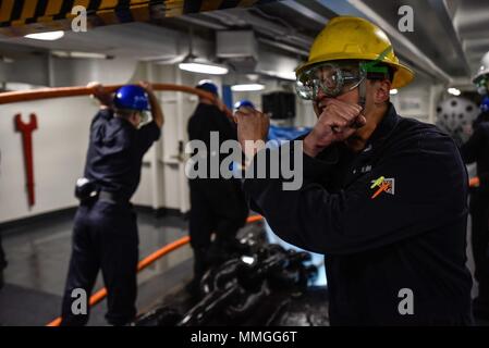 171006-N-CL027-131 PORTO DI HONG KONG (ott. 6, 2017) - di Boatswain Mate 2a classe Tyler Santos, destro da Sunol, California, segnali avast alla corsa operatore nel castello di prua della Marina è distribuita portaerei USS Ronald Reagan (CVN 76), in quanto la nave recupera il dispositivo di ancoraggio dopo una porta programmata visita a Hong Kong. Durante la visita di porta, marinai hanno partecipato le relazioni tra comunità eventi; Morale, il benessere degli animali e la ricreazione tours; e gli eventi sportivi con Hong Kong. Ronald Reagan, il portabandiera del Carrier Strike gruppo 5, fornisce un combattimento-pronto forza che protegge e defen Foto Stock