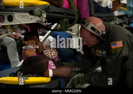 Stati Uniti Air Force Tech. Sgt. Frank Balisciano, assegnato per il quarantacinquesimo di medicina aeronautica squadrone di evacuazione, interagisce e i comfort di un paziente giovane a bordo di una C-17 Globemaster III mentre lungo il tragitto da St. Croix di Dobbins Air Base di riserva, Ga., Sett. 24, 2017. Cittadino di riserva Gli aviatori hanno stabilito le operazioni a MacDill AFB Fla. a sostegno di sforzo umanitario per le isole colpite dall'uragano Maria. (U.S. Air Force foto di Tech. Sgt. Peter Dean) Foto Stock