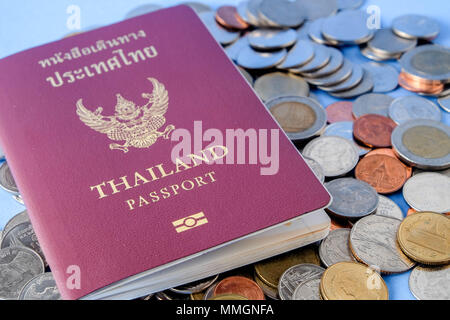 Thailandia passaporto coperchio marrone e denaro moneta su carta blu sfondo per viaggiare in vacanza Foto Stock