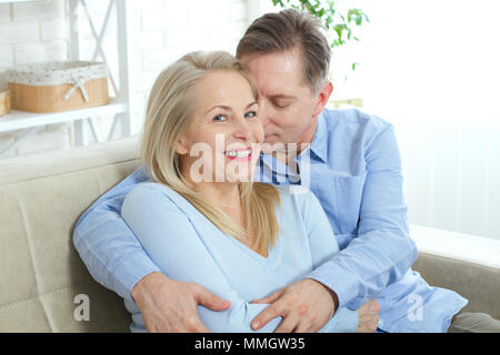 Close up foto di allegro eccitato felice felicemente felice con toothy sorriso splendente bionda attraente donna e uomo, egli abbraccia il suo da dietro e baci Foto Stock