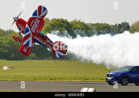 Il pilota temerario Richard Goodwin ha volato il suo Pitts biplano speciale a fianco di una Jaguar F-ritmo lungo la pista a Abingdon. Foto Stock