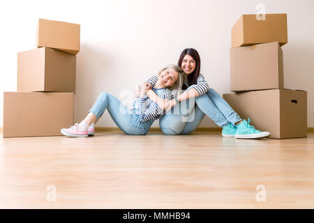 Foto di due ragazze seduta sul pavimento tra le scatole di cartone Foto Stock