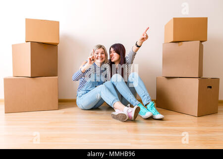 Foto di due ragazze seduta sul pavimento tra le scatole di cartone Foto Stock
