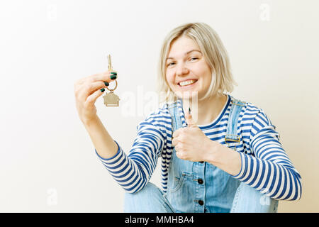 Immagine di donna con chiavi da appartamento contro il muro grezzo Foto Stock