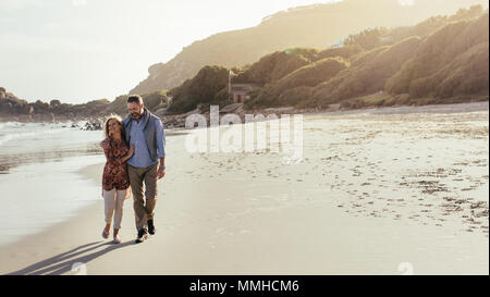 Lunghezza piena ripresa esterna di amorevole coppia senior camminando lungo la spiaggia. Uomo maturo e la donna per passeggiare sulla riva del mare. Foto Stock