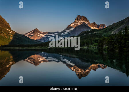 Swiftcurrent Lago e riflessi di Grinnel e Punto di Mount Henkel all'alba nel Parco Nazionale di Glacier, Montana, USA. Foto Stock