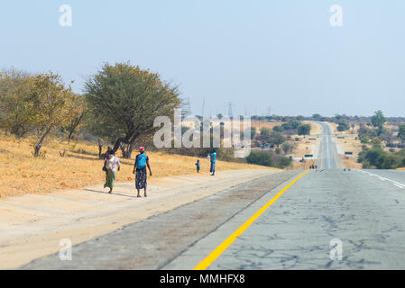 Povera gente che camminava sul ciglio della strada nelle zone rurali Caprivi Strip, la più popolosa regione in Namibia, Africa. Foto Stock