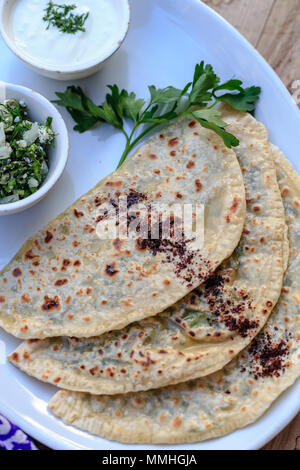 Tradizionale cucina azerbaigiana. Vista superiore colpo di qutabs flatbread con verdi. Foto Stock