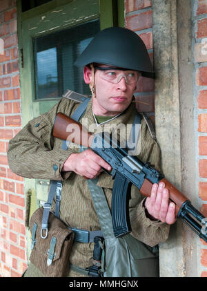 Un soffice come l'aria giocatore indossa Tedesco orientale, 1975, Junior Non-Commissioned ufficiali uniforme con un AK-47 automatic fucile da assalto, il Kalashnikov Foto Stock