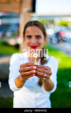 Bella donna tenendo una margherita nelle sue mani Foto Stock