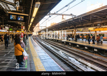 Tokyo, stazione di Shinjuku, Linea Yamanote. Vista lungo la piattaforma e le vie. Molte persone in attesa sulla piattaforma, d'inverno. Ore diurne. Foto Stock