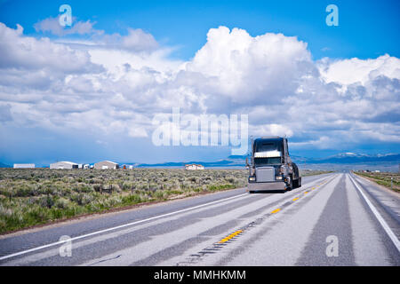 Black classic long haul big rig semi carrello il trasporto commerciale cargo coperto con telo sul letto piano semi rimorchio nell'appartamento strada diritta in Nevad Foto Stock