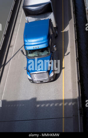 Blu popolare classica big rig semi carrello trattore portare dry van semi rimorchio con spoiler sulla parte anteriore di guida su strada cavalcavia intersezione lungo la r Foto Stock