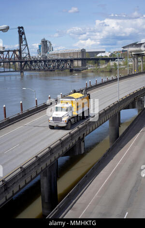 Big Rig potente classico giallo ribaltabile semi autocarro con cassone coperto porta commerciale cargo in esecuzione sul cavalcavia intersezione strada lungo il fiume e Foto Stock