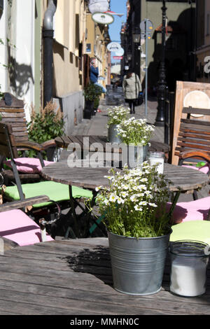 Poznan, Polonia, luglio 30, 2018: tabelle in una street cafe decorate con pentole con lobularia. Coperte bianche sulle spalle di sedie Foto Stock