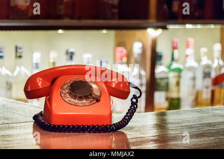 Un'annata di plastica arancione telefono con linea collocato su un tavolo di legno all'interno di un bar. Foto Stock