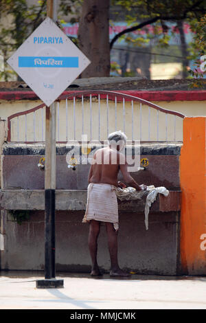 Uomo a lavare i panni a Piparaya stazione ferroviaria, India Foto Stock