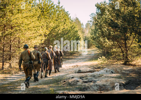 Gruppo di re-enactors vestito come Soviet russo Rosso esercito di soldati di fanteria della II Guerra Mondiale in marcia lungo la strada forestale in estate stagione autunnale. Foto Stock