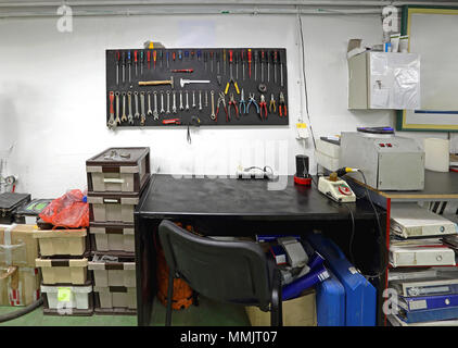 Gli strumenti a mano a bordo della parete e scrivania da lavoro in officina Foto Stock