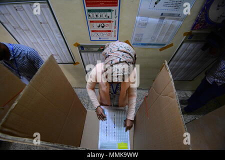 Baghdad in Iraq. Il 12 maggio 2018. Una donna irachena zecche il suo turno di scrutinio dietro una cabina di voto durante le elezioni parlamentari in corrispondenza di una stazione di polling a Baghdad, Iraq, 12 maggio 2018. Quasi 7.000 candidati sono in lizza per i posti a sedere in 329-Parlamento forte, che saranno in seguito eleggere Iraq·s presidente e primo ministro. Credito: Ameer Al Mohammedaw/dpa/Alamy Live News Foto Stock