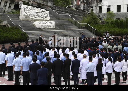 Wenchuan, cinese della provincia di Sichuan. Il 12 maggio 2018. Le persone si radunano presso il sito rovina di Xuankou Middle School come essi partecipare ad una cerimonia commemorativa segna il decimo anniversario del Wenchuan terremoto a Yingxiu Township della contea di Wenchuan, a sud-ovest della Cina di provincia di Sichuan, 12 maggio 2018. Una grandezza 8 terremoto ha colpito la contea di Wenchuan del 12 maggio 2008, lasciando più di 69.000 morti, feriti 374,000, 18.000 mancante e milioni di senzatetto. Credito: Liu Kun/Xinhua/Alamy Live News Foto Stock