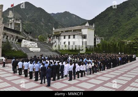 Wenchuan, cinese della provincia di Sichuan. Il 12 maggio 2018. Le persone si radunano presso il sito rovina di Xuankou Middle School come essi partecipare ad una cerimonia commemorativa segna il decimo anniversario del Wenchuan terremoto a Yingxiu Township della contea di Wenchuan, a sud-ovest della Cina di provincia di Sichuan, 12 maggio 2018. Una grandezza 8 terremoto ha colpito la contea di Wenchuan del 12 maggio 2008, lasciando più di 69.000 morti, feriti 374,000, 18.000 mancante e milioni di senzatetto. Credito: Liu Kun/Xinhua/Alamy Live News Foto Stock