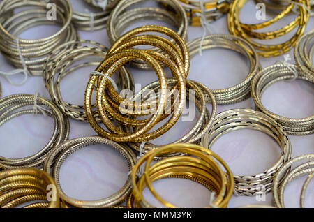 Un primo piano di bracciali metallici legati insieme con un filo di lana. I bracciali sono stati esposti per la vendita a Shilparamam, Hyderabad, India. Foto Stock