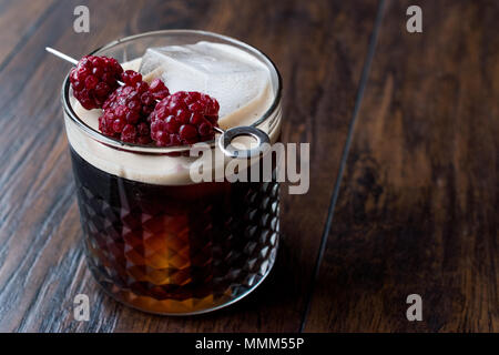 Nero / birra scura cocktail con more e ghiaccio sulla superficie di legno. Concetto di bevanda. Foto Stock