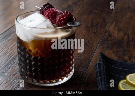 Nero / birra scura cocktail con more e ghiaccio sulla superficie di legno. Concetto di bevanda. Foto Stock