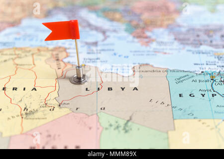 Piccola bandiera rossa segna il paese africano di Libia su una mappa del mondo. Foto Stock