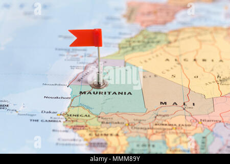 Piccola bandiera rossa segna il paese africano della Mauritania su una mappa del mondo. Foto Stock