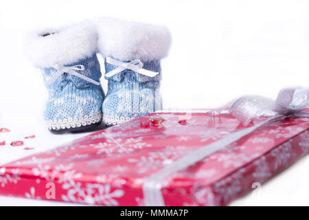 Little Christmas scarponi invernali avvolto intorno a un dono su sfondo bianco Foto Stock