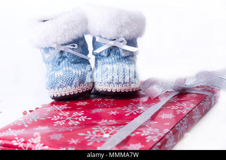 Little Christmas scarponi invernali avvolto intorno a un dono su sfondo bianco Foto Stock