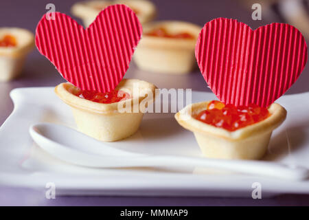 Tortine con caviale rosso e cuori di carta il giorno di San Valentino Foto Stock