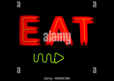 Una scritta al neon con la parola mangiare e una freccia che indica la direzione. Foto Stock